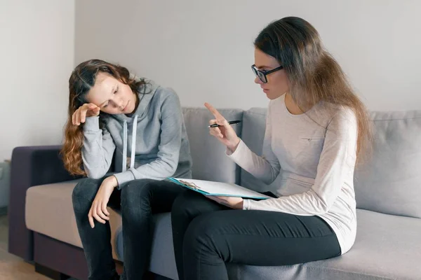 Молода жінка професійний психолог розмовляє з дівчиною-підлітком 14, 15 років, сидячи в офісі на дивані. Психічне здоров'я дитини в підлітковому віці — стокове фото