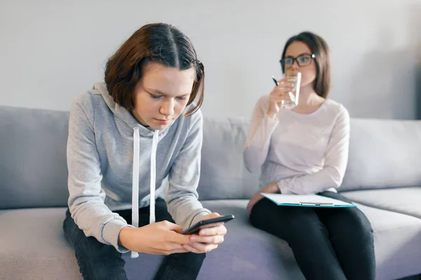 Dospívající dívka pacienta mluvit s profesionální psychoterapeut v úřadu. Dívka vypadá do její telefon ignoruje psycholog. — Stock fotografie