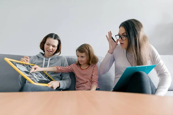 Две сестры девочки разговаривают с молодой женщиной семейный психолог, дети сидят в офисе — стоковое фото