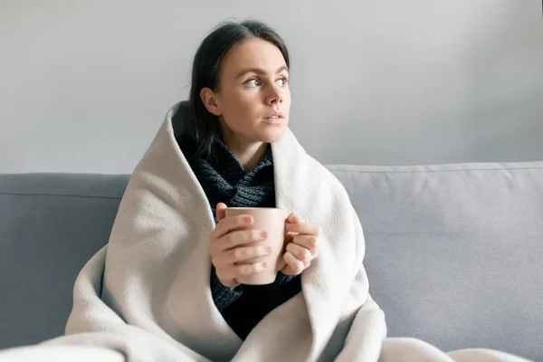 Höst vinter porträtt av ung flicka vilar hemma i soffan med kopp varm dryck, under varma filt — Stockfoto