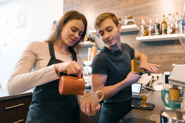 Jovem casal homem e mulher proprietários pequeno negócio café, trabalhando perto de máquinas de café, fazendo bebidas — Fotografia de Stock