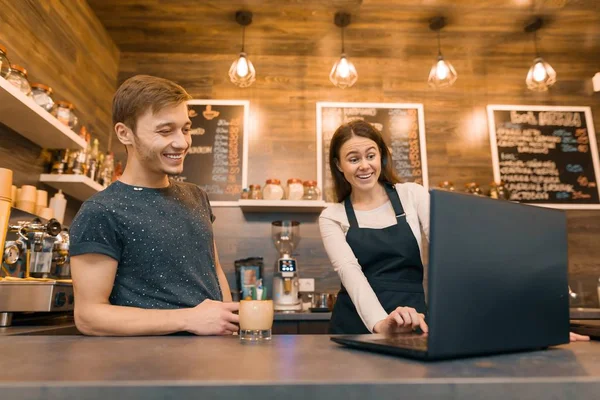 Joven pareja de hombres y mujeres propietarios de una pequeña cafetería moderna con ordenador portátil para el trabajo — Foto de Stock