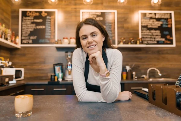 Portrait of smiling young female coffee shop owner, confident woman standing at the counter