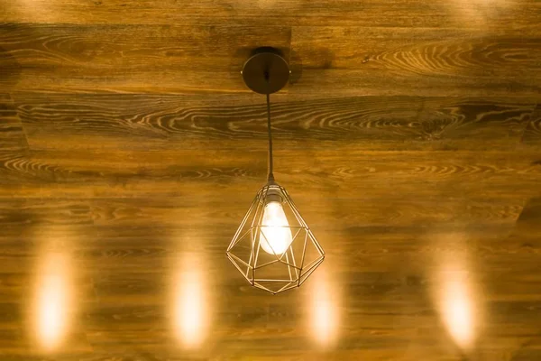 Moderna elegante lampada geometrica su un soffitto di legno marrone bronzo — Foto Stock