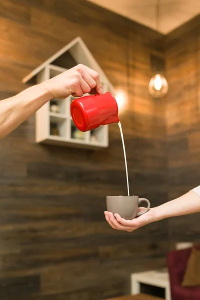 Closeup of pouring steamed milk into coffee cup, coffee shop background — Stock Photo, Image