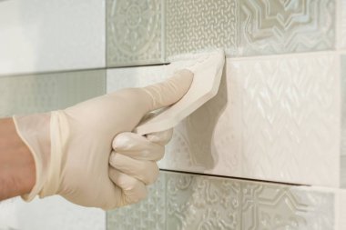 Closeup of tiler hand rubbing tile, Installing and grouting decorative finishes in environments with an high aesthetic value. Two-component, decorative, acid resistant epoxy grout clipart