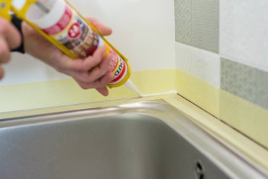 Kyiv, Ua, 15-03-2019. Dikiş silikon dolgu macunu ile duvar ve mutfak tezgah üzerinde seramik karolar arasında işçi inşaat şırınga ile doldurur.