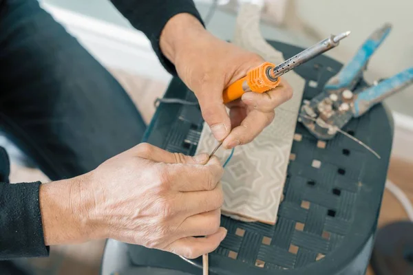 Varón que sostiene la reparación de herramientas de soldador, conexión de alambre eléctrico, soldadura con un soldador — Foto de Stock