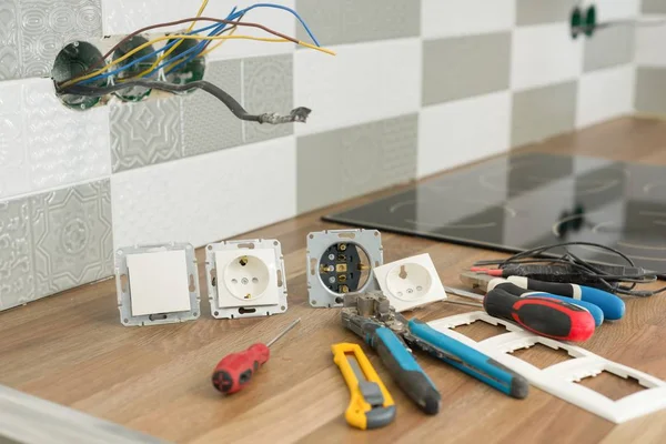 Preparing to install an electrical outlet. Closeup of professional electrician tools and electrical outlets. Renovation and construction in kitchen. — Stock Photo, Image