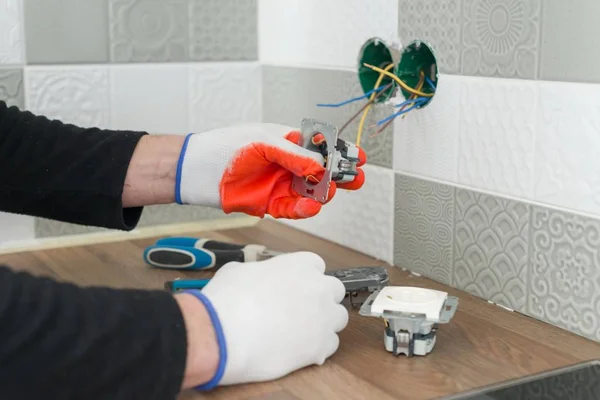 Renovação e construção na cozinha, close-up de eletricistas mão instalar tomada na parede com telhas cerâmicas usando ferramentas profissionais — Fotografia de Stock