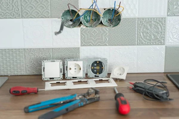 Preparando para instalar uma tomada elétrica. Closeup de ferramentas de eletricista profissional e tomadas elétricas. Renovação e construção em cozinha . — Fotografia de Stock