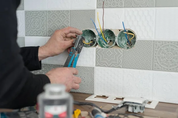 Rekonstrukce a výstavba v kuchyni, detail ruky elektrikáři instalací zásuvky na zdi s keramickými obklady, pomocí profesionálních nástrojů — Stock fotografie