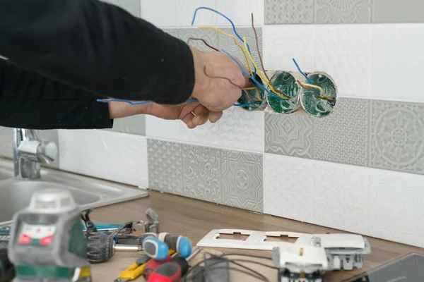 Renovierung und Bau in der Küche, Nahaufnahme der Elektriker Hand Installation Steckdose an der Wand mit keramischen Fliesen mit professionellen Werkzeugen — Stockfoto