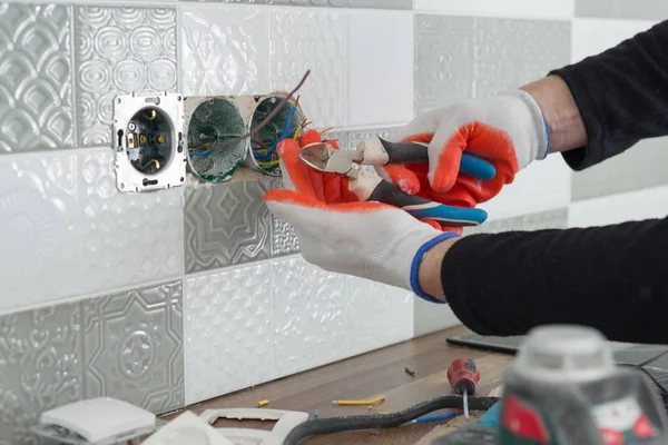 Renovatie en nieuwbouw in keuken, close-up van elektriciens hand stopcontact installeren op muur met keramische tegels met behulp van professionele gereedschappen — Stockfoto