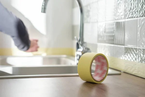 Trabajador que protege la encimera en la cocina con cinta adhesiva antes de comenzar las reparaciones de construcción con baldosas cerámicas — Foto de Stock