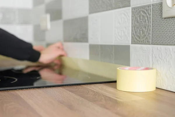 Trabajador que protege la encimera en la cocina con cinta adhesiva antes de comenzar las reparaciones de construcción con baldosas cerámicas — Foto de Stock