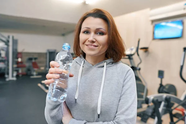 Porträt einer lächelnden Sommerfrau mit einer Flasche Wasser im Fitnessstudio. Gesundheit Fitness Sport Alterskonzept — Stockfoto