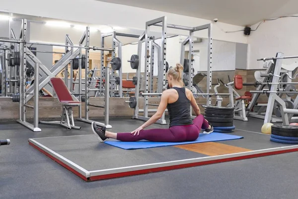 Jeune femme musculaire athlétique faisant de l'exercice d'étirement dans la salle de gym, femme pratiquant le yoga — Photo