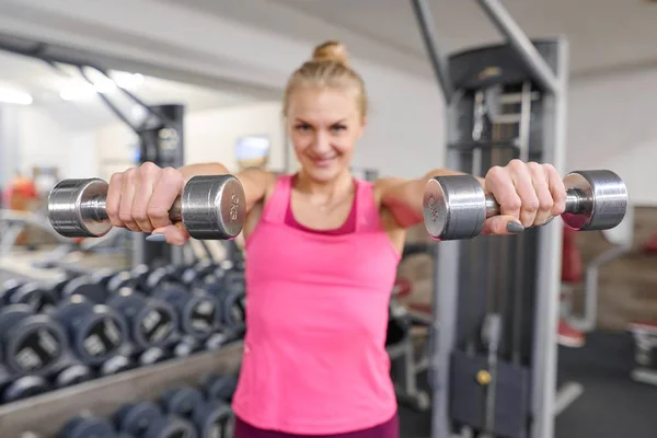 Jeune femme blonde sportive dans la salle de gym. Femme tenant des poids métalliques, se concentrer sur kettlebells. Personnes fitness sport mode de vie sain concept — Photo