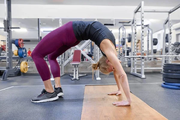 Giovane donna bionda sportiva che allunga il corpo mentre fa esercizi di yoga in palestra — Foto Stock