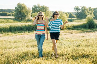 Mutlu anne ve gülümseyen ve konuşurken teen kızı. Doğada bir güneşli yaz gününde yürüyüş