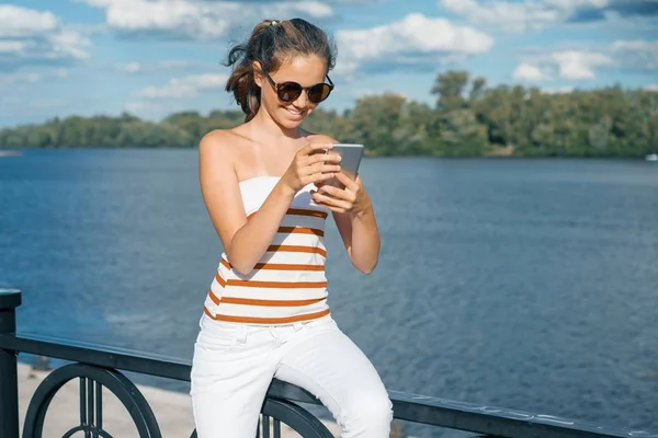 Jong meisje blogger neemt foto's en video's voor zijn blog. Meisje glimlachend op de straat van het zomer-stadspark — Stockfoto