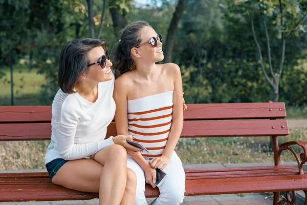 Communication between parent and child. Mom and daughter teenager talking and laughing while sitting on the bench in the park — Stock Photo, Image