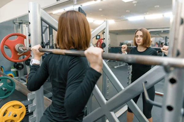 Mujer joven fuerte haciendo ejercicio de peso pesado en el gimnasio. Deporte, fitness, musculación, entrenamiento, estilo de vida y concepto de personas — Foto de Stock