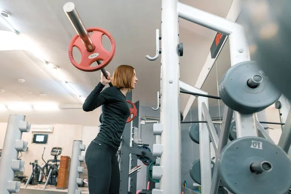 Молодая сильная фитнес-женщина делает силовые упражнения с тяжелой штангой в спортзале. Спорт, тяжелая атлетика, бодибилдинг, тренировки, образ жизни и концепция людей — стоковое фото