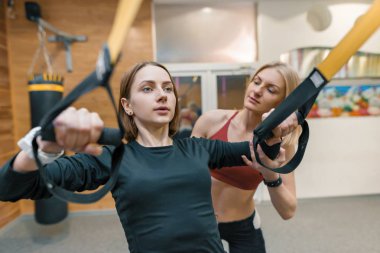 Genç kadın Egzersiz Egzersizler fitness döngü sistemi üzerinde kişisel fitness eğitmeni ile yapıyor. Spor, sporcu, eğitim, yaşam tarzı ve insanlar kavramı