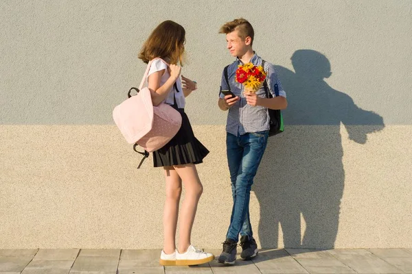 Retrato al aire libre de adolescentes, niño con ramo de flores y niña, fondo de pared gris —  Fotos de Stock