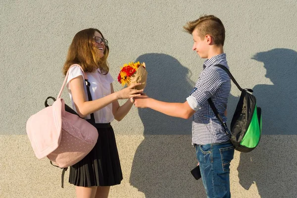 Pojke ger flicka bukett av blommor. Utomhus porträtt av par tonåringar — Stockfoto