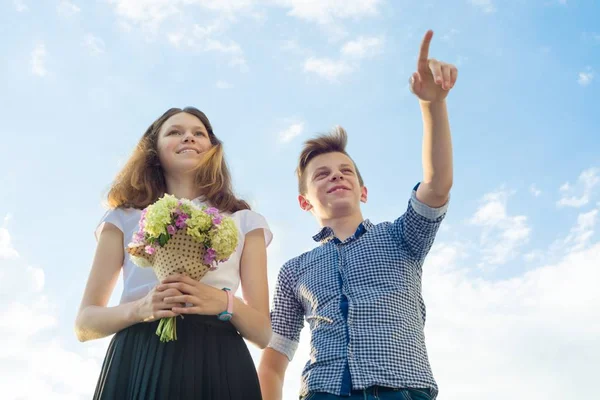 Lyckliga par tonåringar pojke och flicka 14, 15 år gammal. Unga människor ler och talar, blå himmel bakgrund — Stockfoto