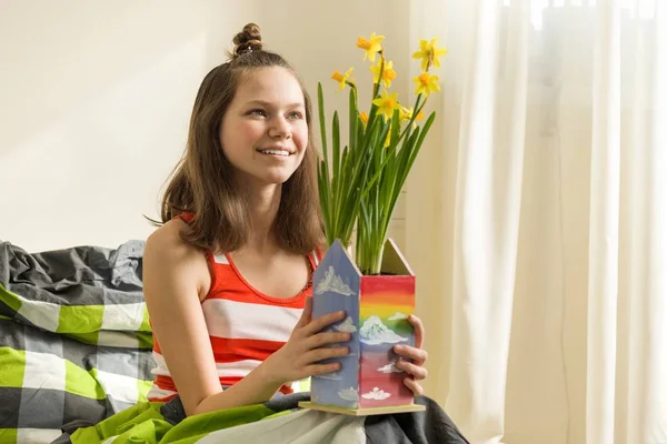 Menina adolescente com buquê de flores amarelas da primavera, sorrindo e feliz sentado em casa na cama — Fotografia de Stock