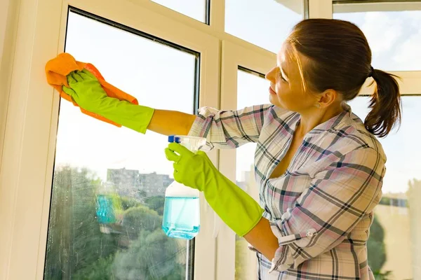 Närbild av kvinna rengöring windows, händer i gummi skyddshandskar, rag och spruta rengöringsmedel — Stockfoto