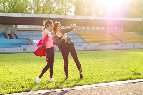 Mother and daughter teenager resting after workout at stadium. Photographed together selfi photo — Stock Photo, Image