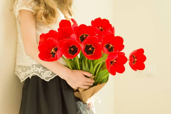 Child girl holding bouquet of red tulips flowers. Gift, surprise, spring family holiday — Stock Photo, Image