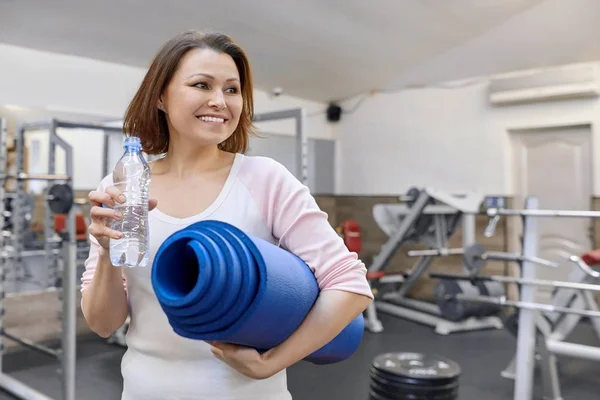 Porträt einer lächelnden reifen Frau mit Wasserflasche und Sportmatte im Fitnessstudio. Gesundheit Fitness Sport Alterskonzept — Stockfoto