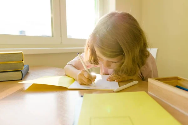 Schoolmeisje, meisje van 8 jaar, zittend aan tafel met boeken en schrijven in de laptop. School, onderwijs, kennis en kinderen — Stockfoto