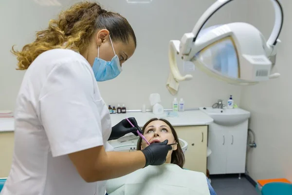 Volwassen vrouwelijke tandarts behandeling van de patiënt vrouw tanden. Geneeskunde, tandheelkunde en healthcare concept — Stockfoto