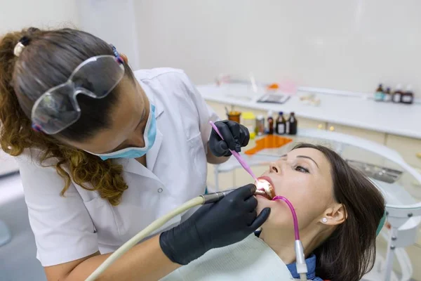 Медицина, стоматологія та концепція охорони здоров'я. Жінка-стоматолог використовує стоматологічне лікування УФ лампи на зубах пацієнта — стокове фото