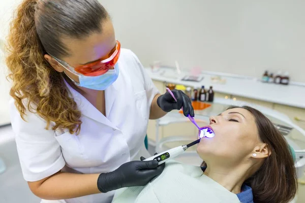 Dentista mujer adulta tratando dientes de mujer paciente. Medicina, odontología y concepto sanitario — Foto de Stock