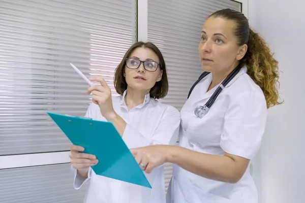 Duas mulheres médico e cirurgião conversando no hospital no fundo da porta — Fotografia de Stock