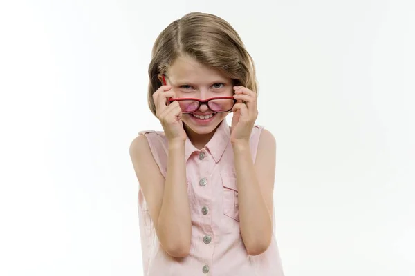 Ganska leende flicka elev i glasögon på vit bakgrund, isolerad. Leende barn tittar in i kameran med sina glasögon ner. — Stockfoto