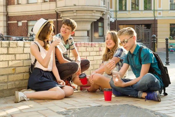 Feliz 4 amigos adolescentes ou estudantes do ensino médio estão se divertindo, conversando, lendo telefone, livro. Conceito de amizade e pessoas, cidade rua fundo — Fotografia de Stock