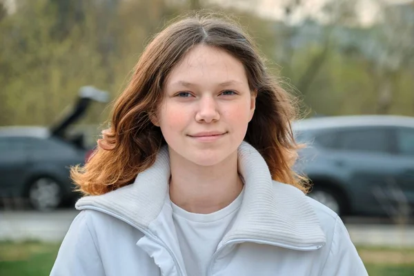 Outdoor portrait of teenager girl 15 years old, girl smiling with long brown hair in white jacket — Stock Photo, Image