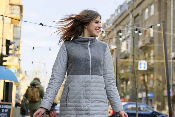Молодая красивая улыбающаяся женщина, идущая по улице весеннего города — стоковое фото