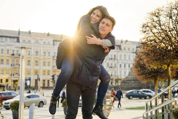 Couple de beaux étudiants s'amusent en ville, arrière-plan ville de printemps, jeune homme et femme riant, heure d'or — Photo