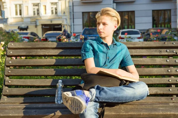 Outdoor Portret van tiener jongen van 13, 14 jaar oud zittend op de Bank in het stadspark. — Stockfoto