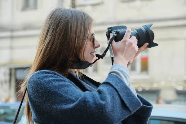 Fiatal gyönyörű lány fényképezőgéppel a tavaszi városban, lány turista fényképez a város utcáján — Stock Fotó